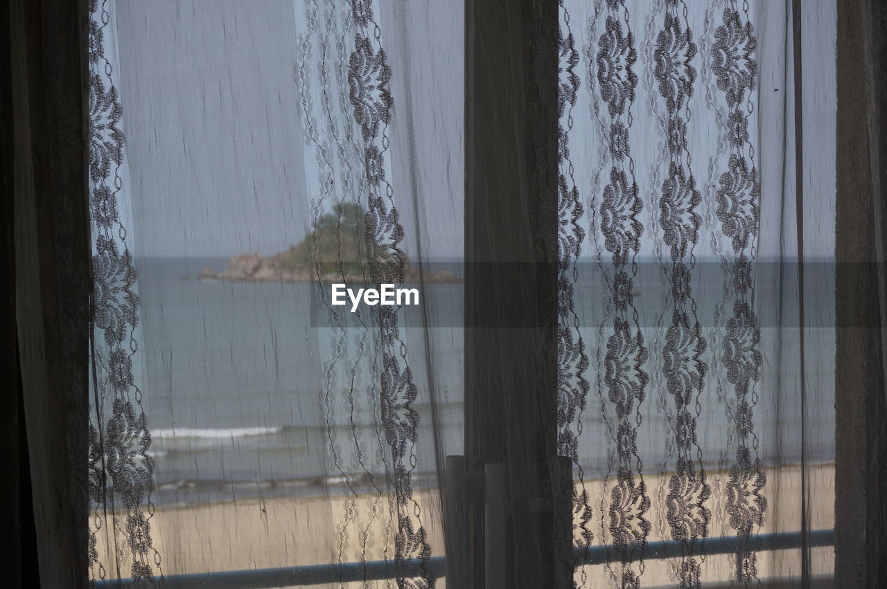 Sea seen through window curtain