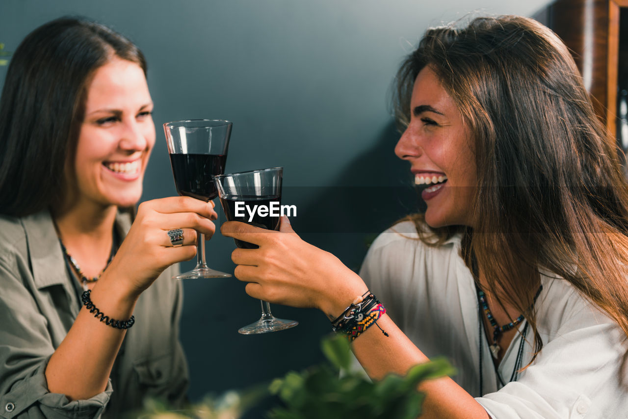 Cheerful female friends toasting wineglasses in restaurant