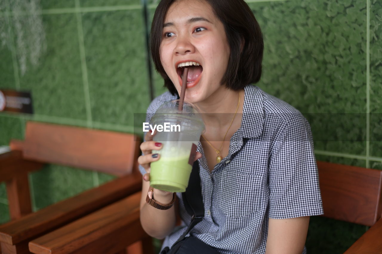  woman with mouth open holding drink at cafe