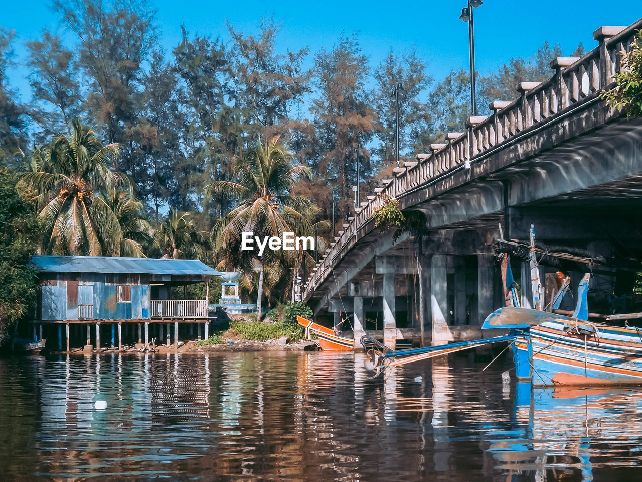 Boats on bridge by trees against sky