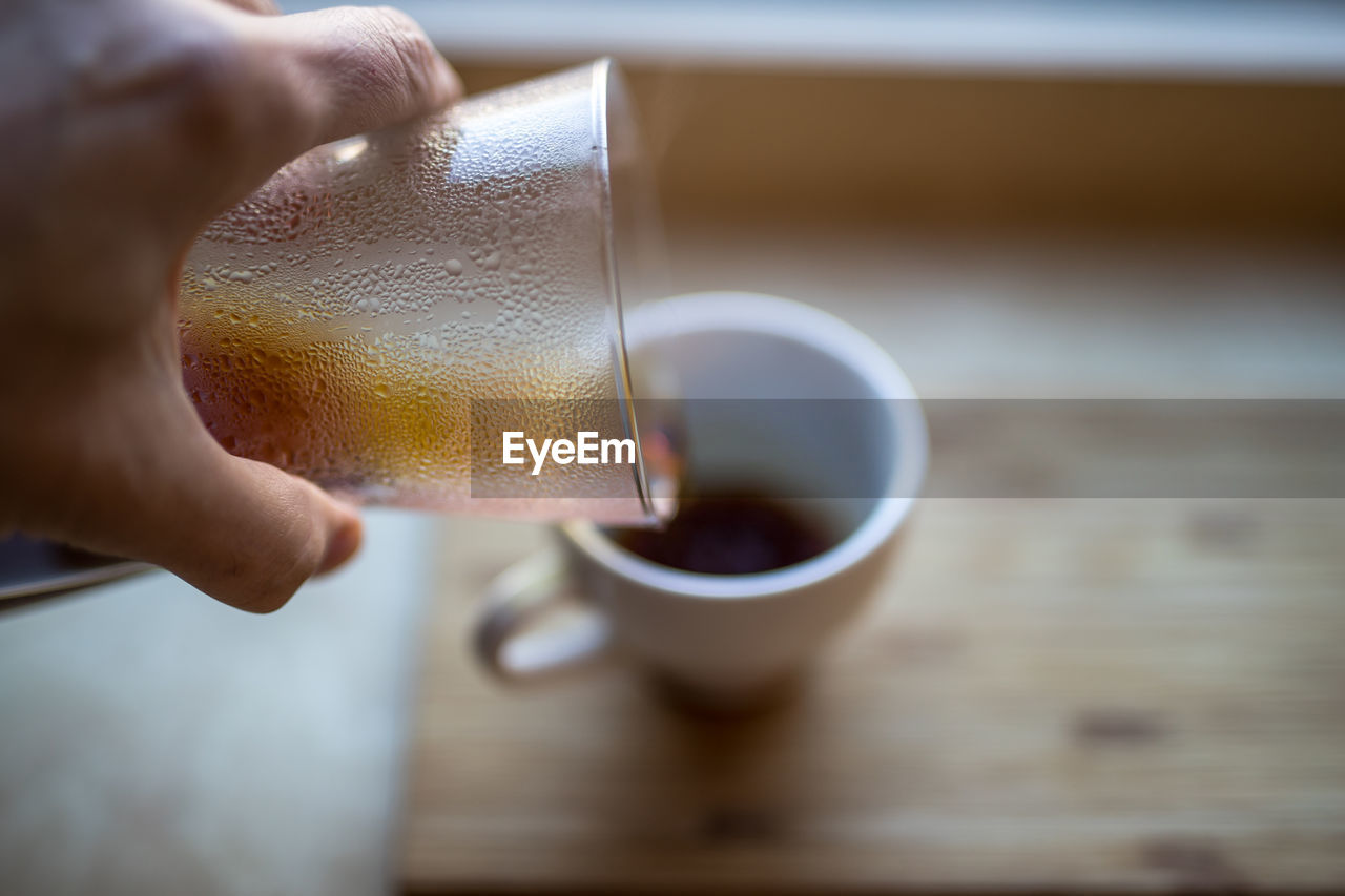 Cropped image of person pouring coffee in cup