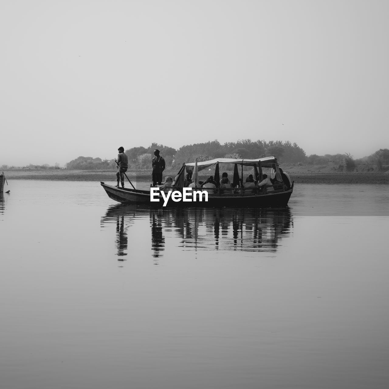 People on rowboat in lake against clear sky