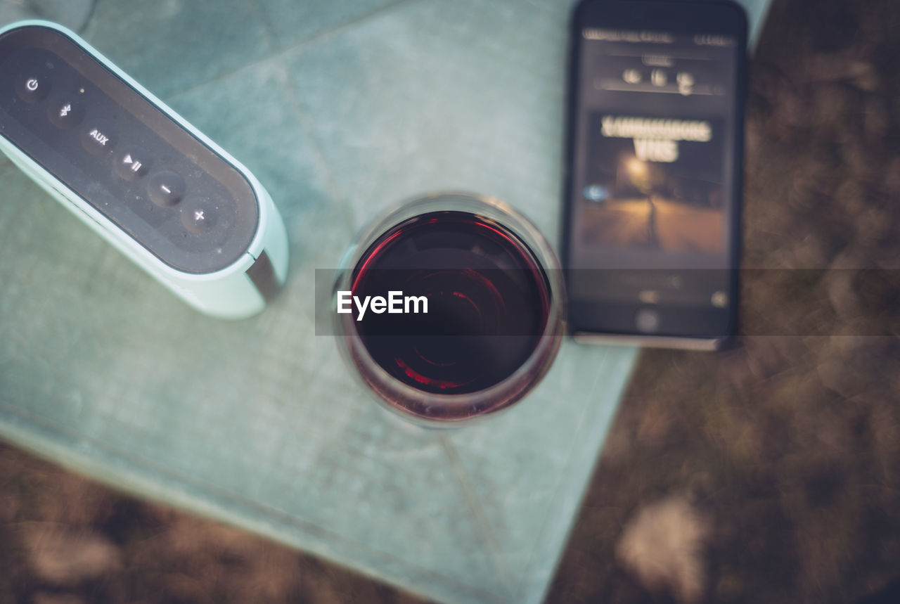 High angle view of wine amidst bluetooth speaker and smart phone on table