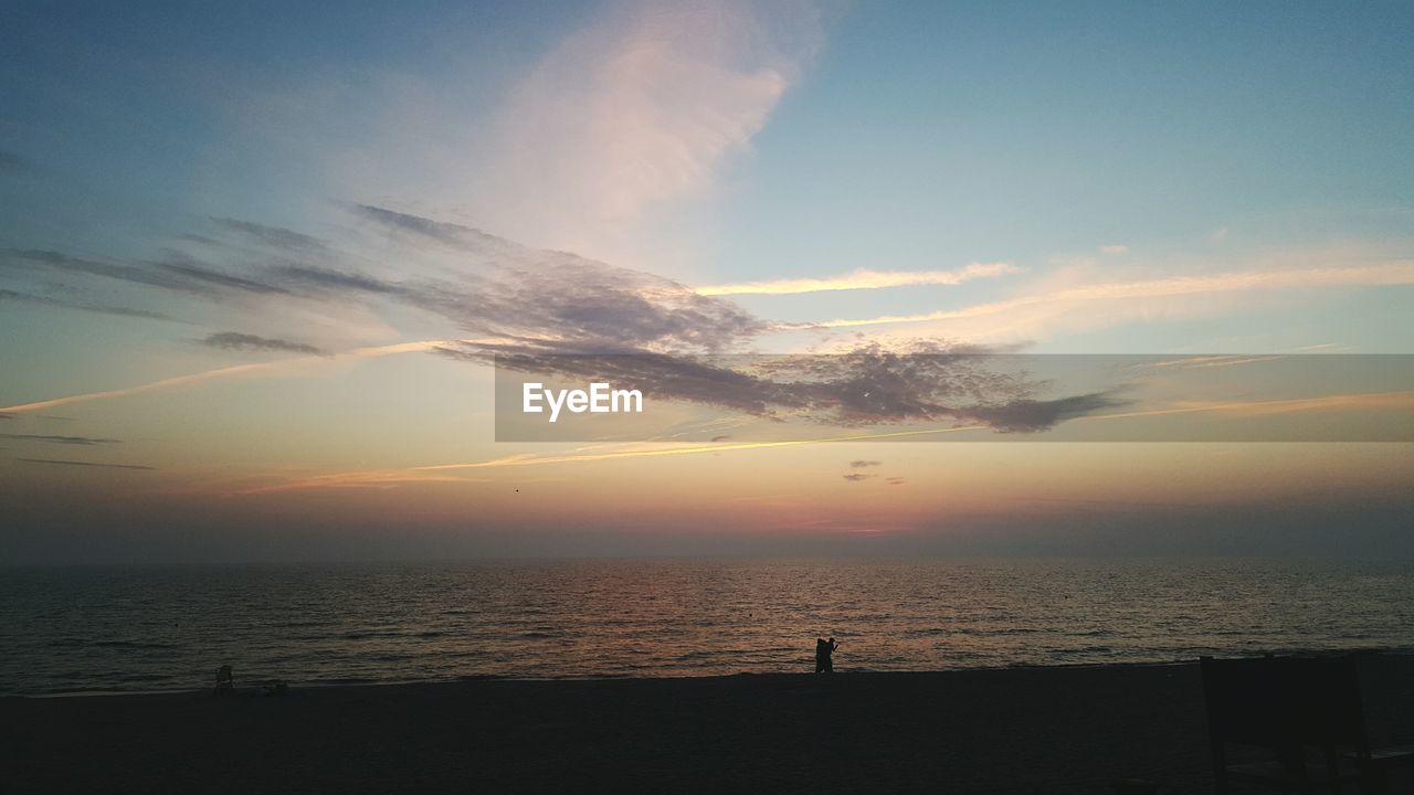 Scenic view of sea against cloudy sky at dusk