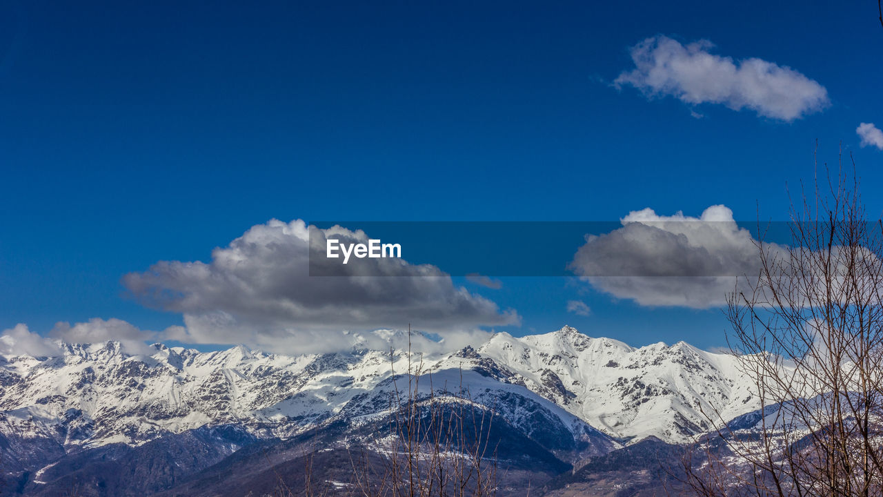 Scenic view of snowcapped mountains against blue sky