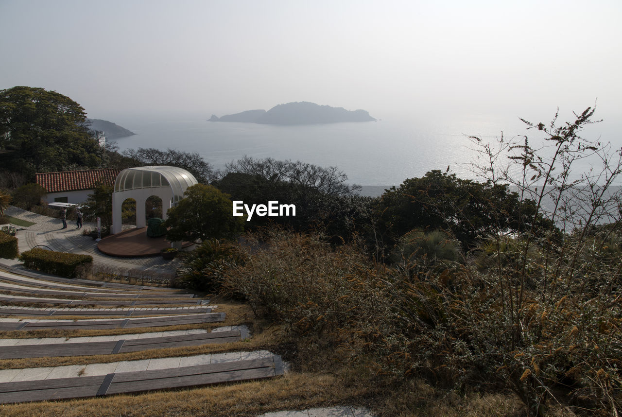 HIGH ANGLE VIEW OF STEPS AMIDST BUILDINGS AND TREES AGAINST SKY