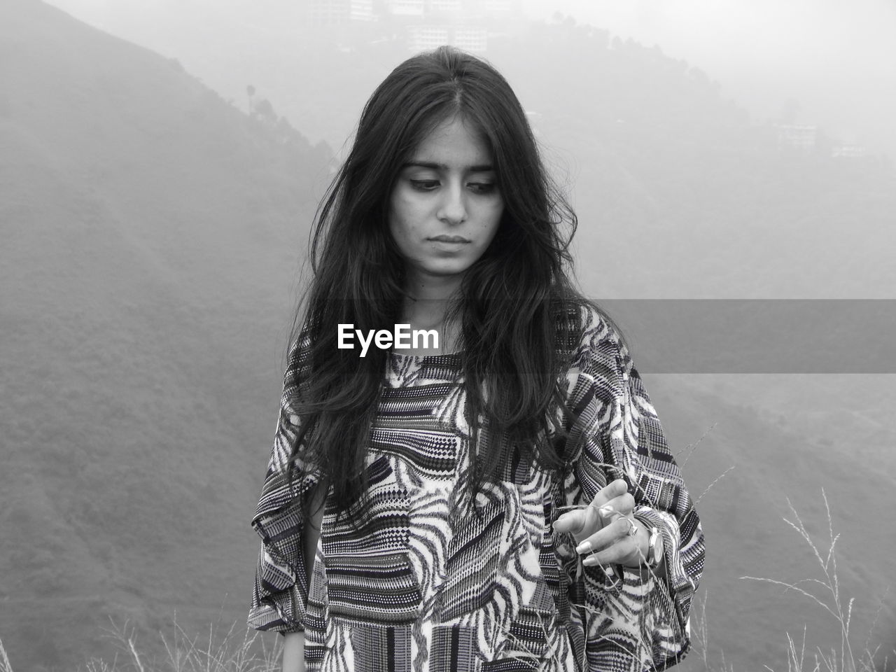 Young woman looking away standing against mountain range