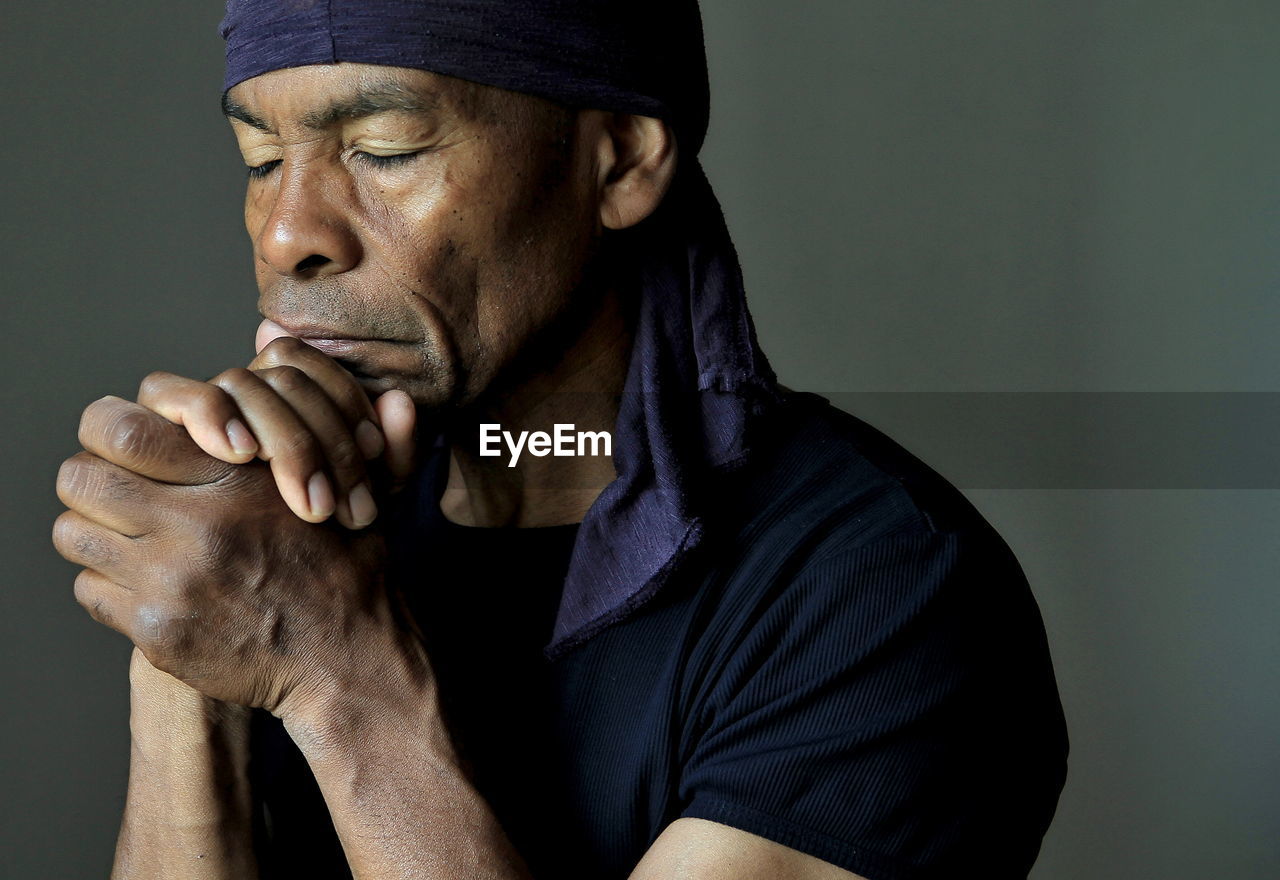 Man praying to god with hands together stock photo	