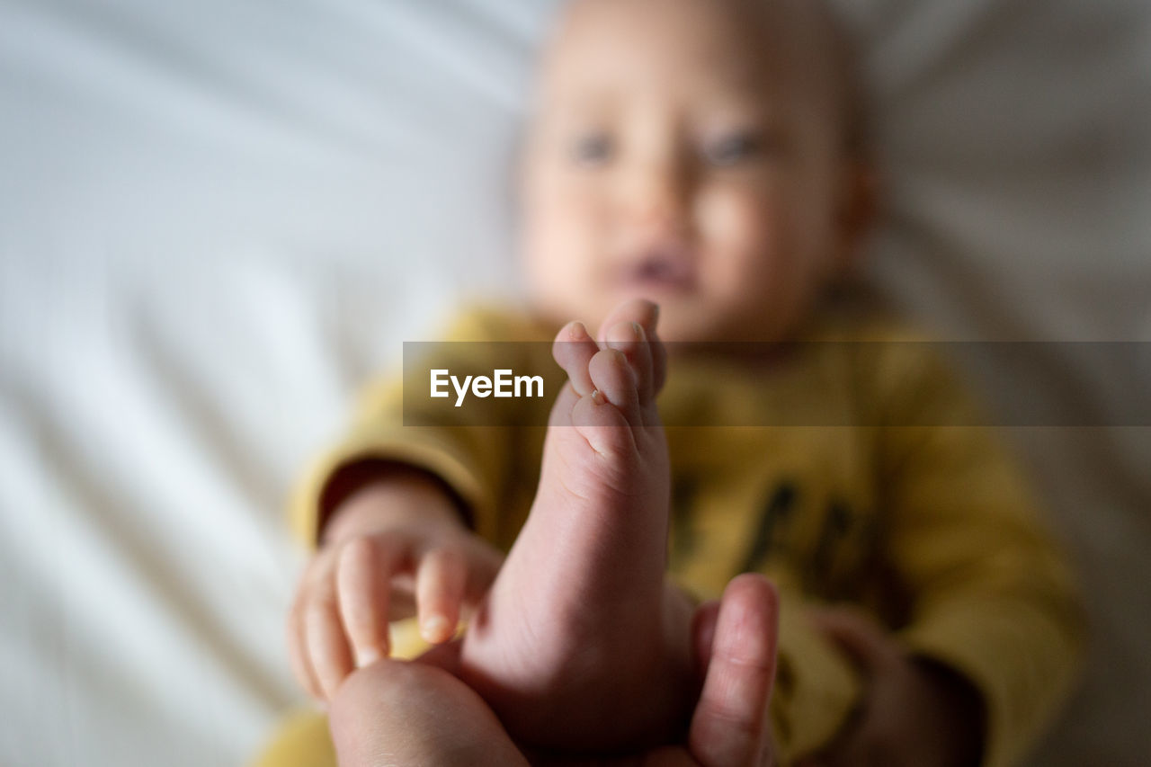Upper view on a lying baby bare foot held by parent hand