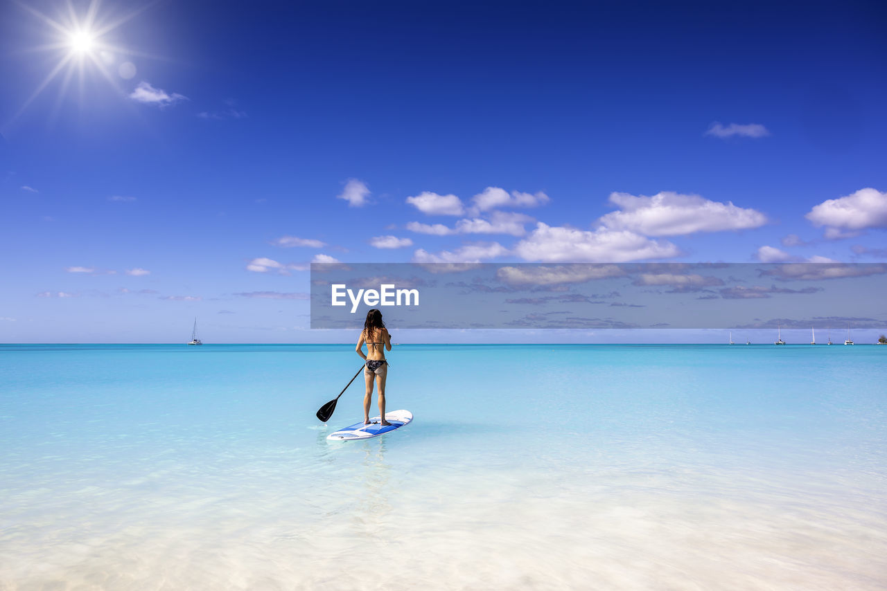 rear view of woman walking on beach against sky