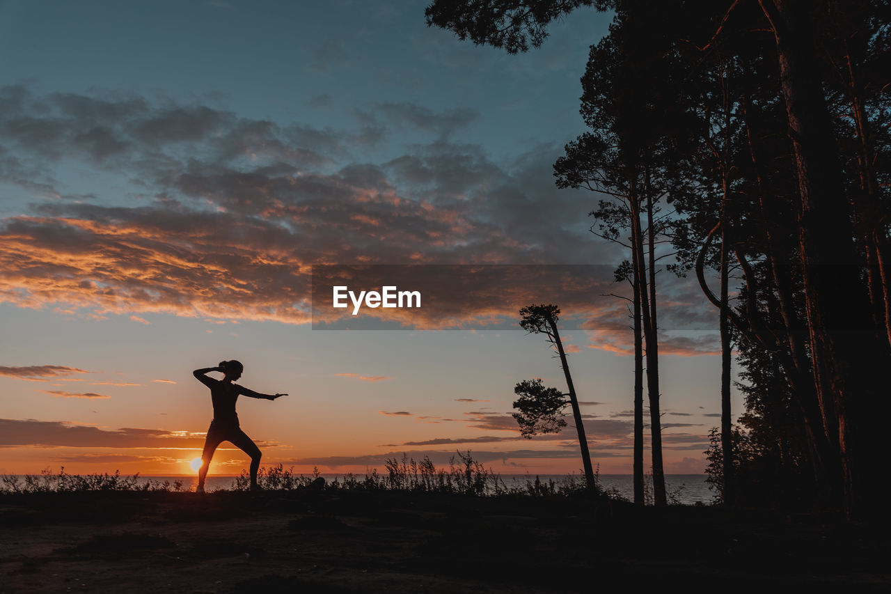 A woman is engaged in karate against the background of the sunset sky