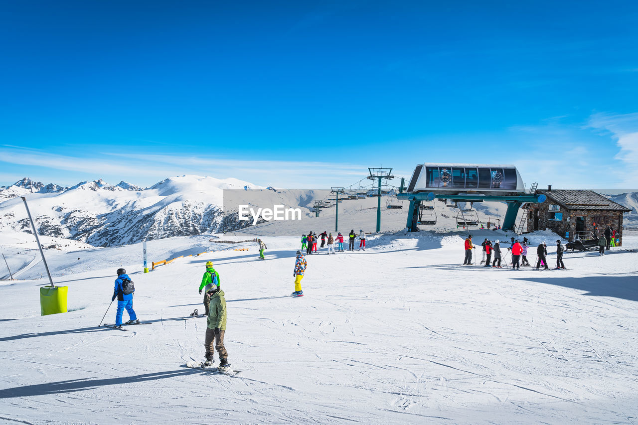 Skiers and snowboarders exiting from ski lift on the top of the mountain in andorra