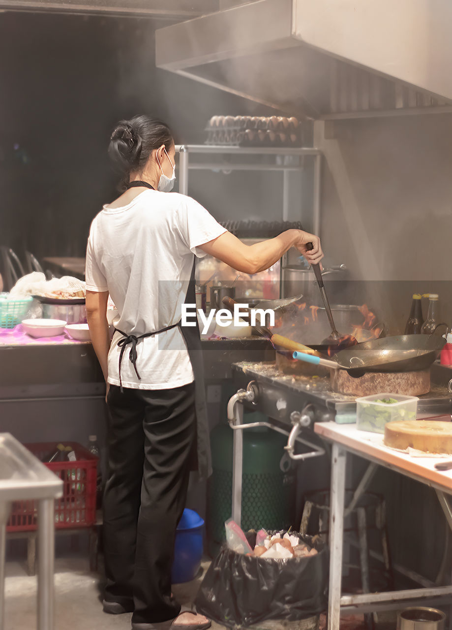 REAR VIEW OF MAN AND WOMAN IN KITCHEN