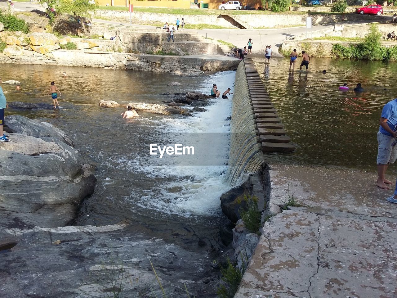 HIGH ANGLE VIEW OF PEOPLE IN WET WATER