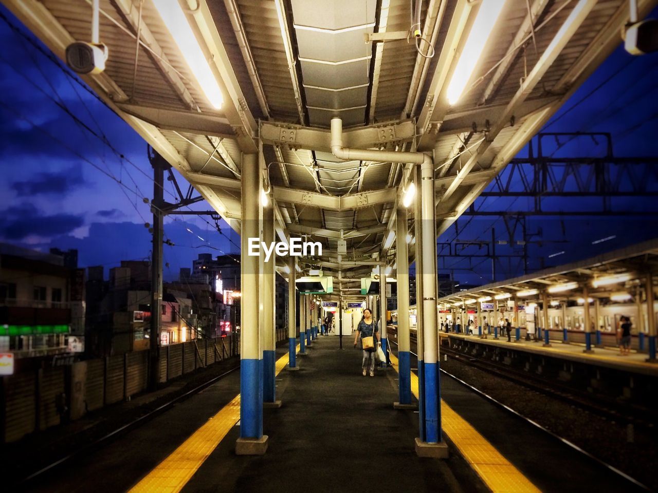 Woman standing on railroad station at night