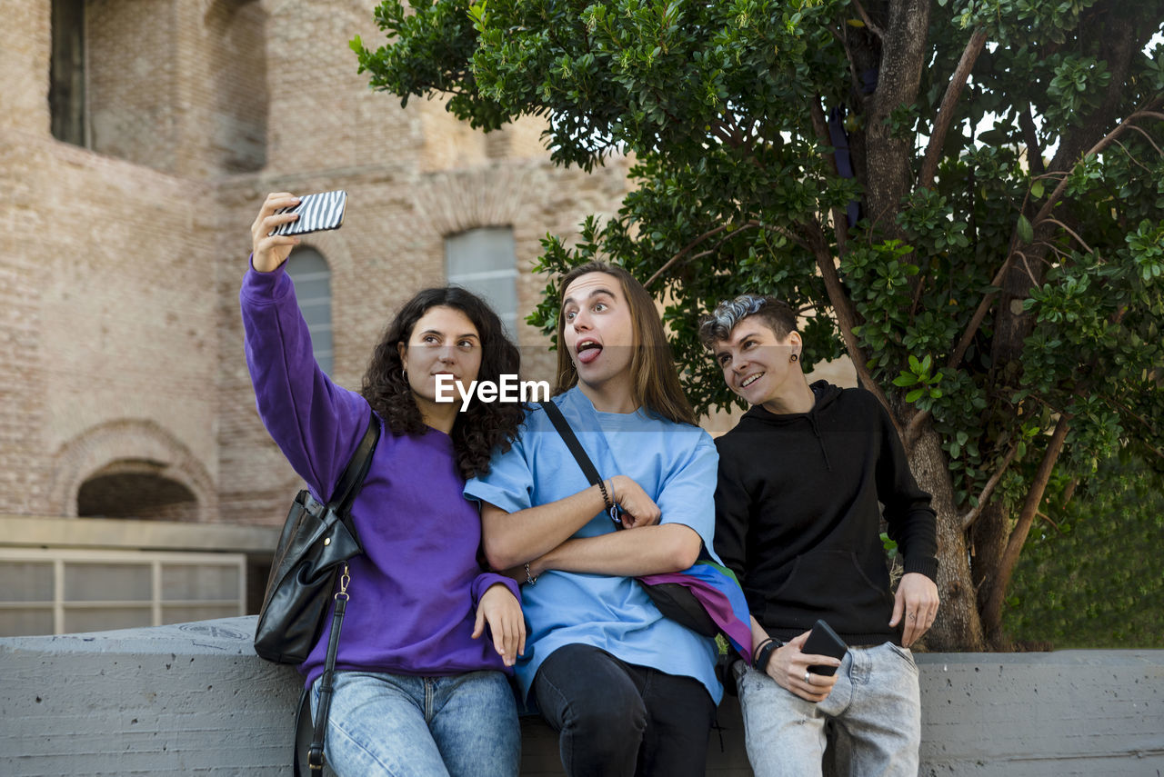 Young diverse friends taking selfie with a mobile phone outdoors.