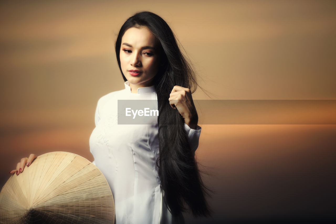 Portrait of beautiful asian girls with ao dai vietnam traditional dress on sunset landscapes.