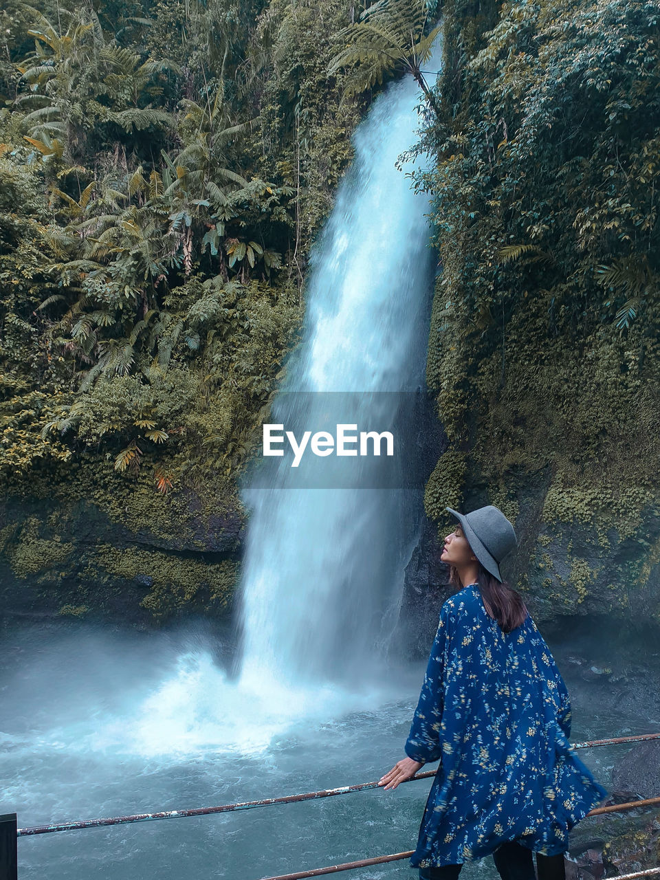 Woman standing on rock against waterfall