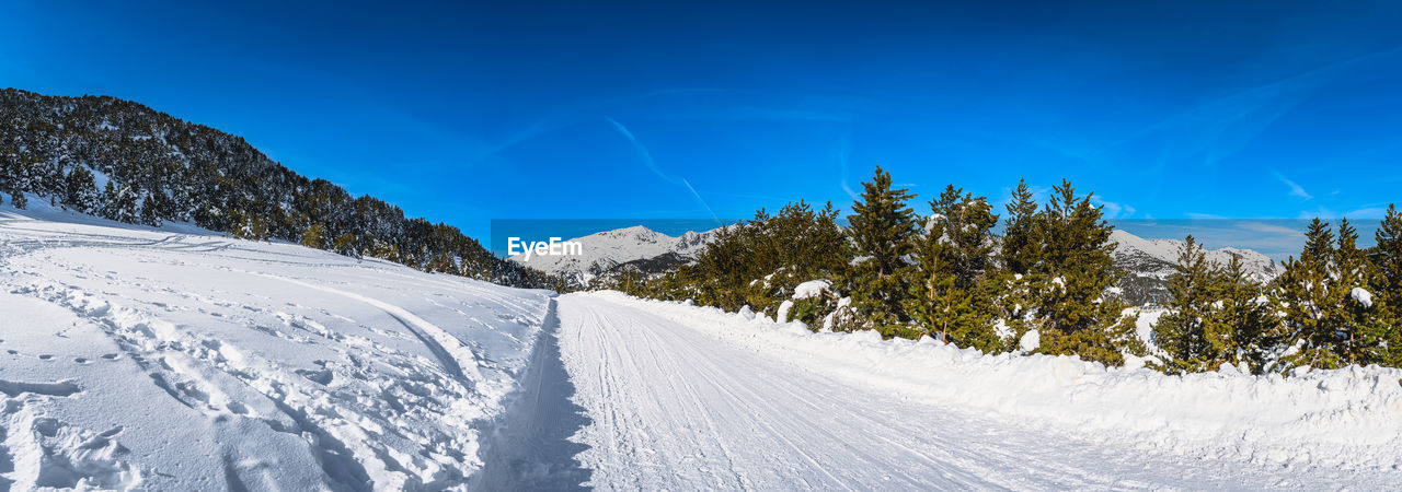 Wide panorama with road leading to snow covered mountains and forest, andorra, pyrenees