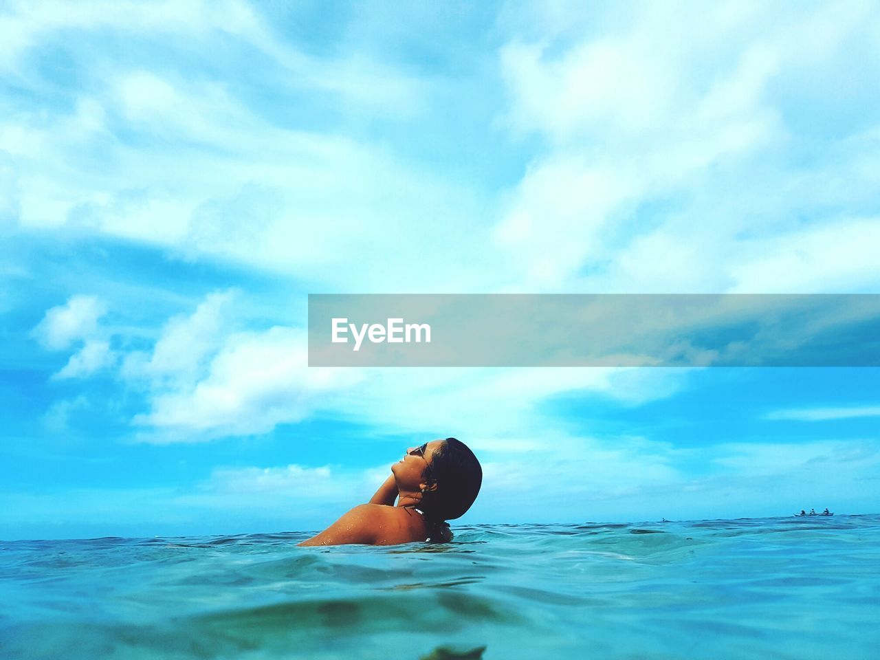 Woman swimming in sea against blue sky