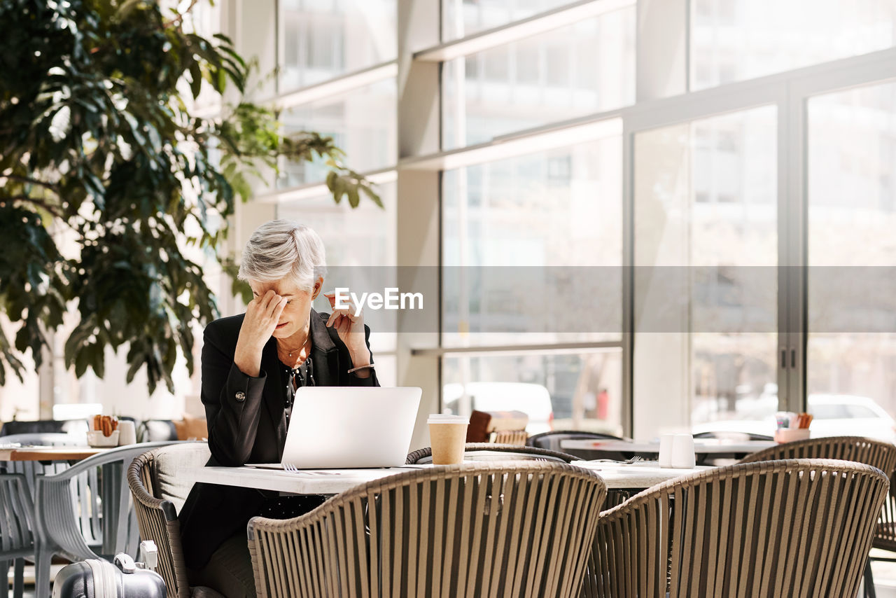 Young woman using phone while sitting on table