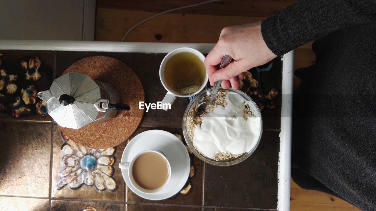 Midsection of woman having breakfast in kitchen