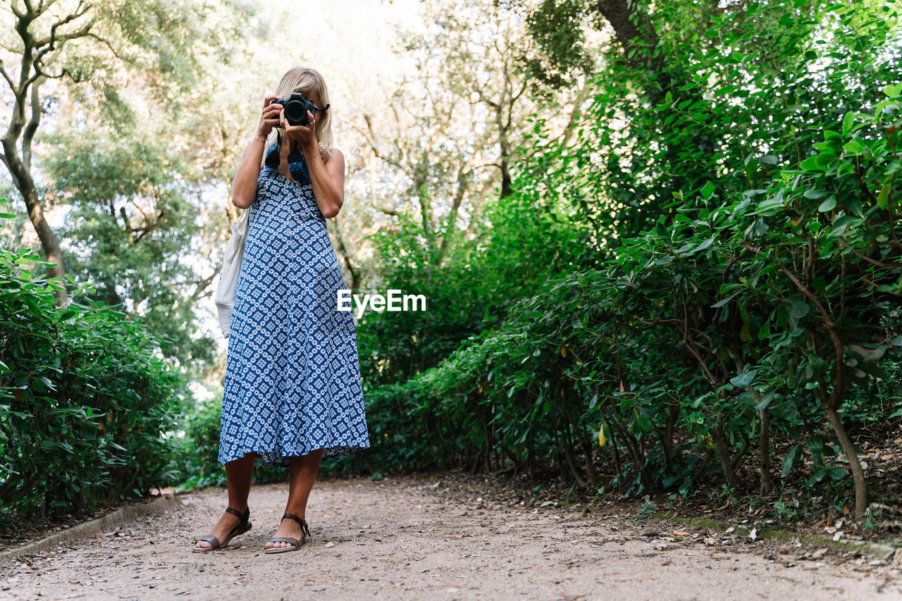 Woman in blue dress standing while taking a picture in a park