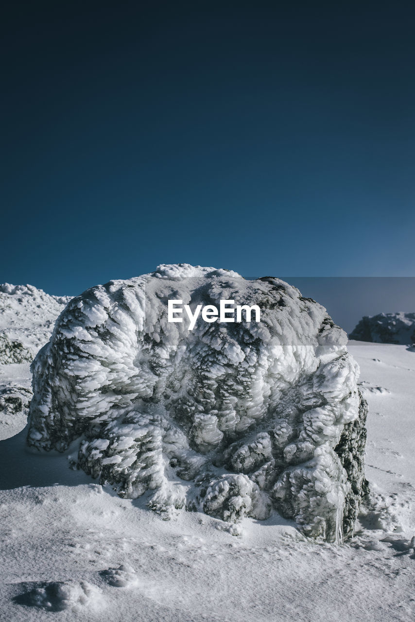 Snowcapped landscape against clear blue sky