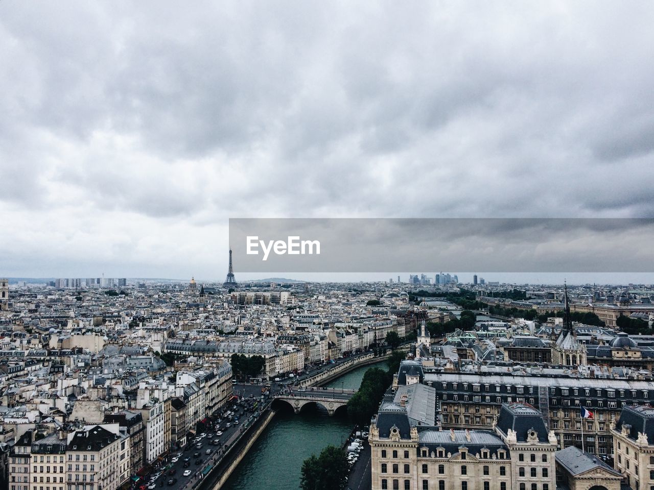 Cityscape with eiffel tower in background against cloudy sky