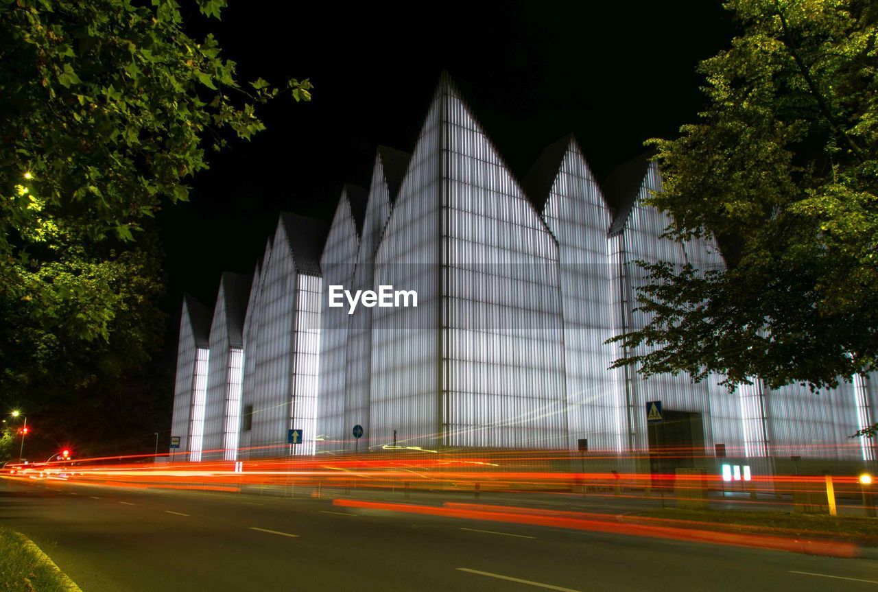 LIGHT TRAILS ON ROAD AGAINST BUILDINGS