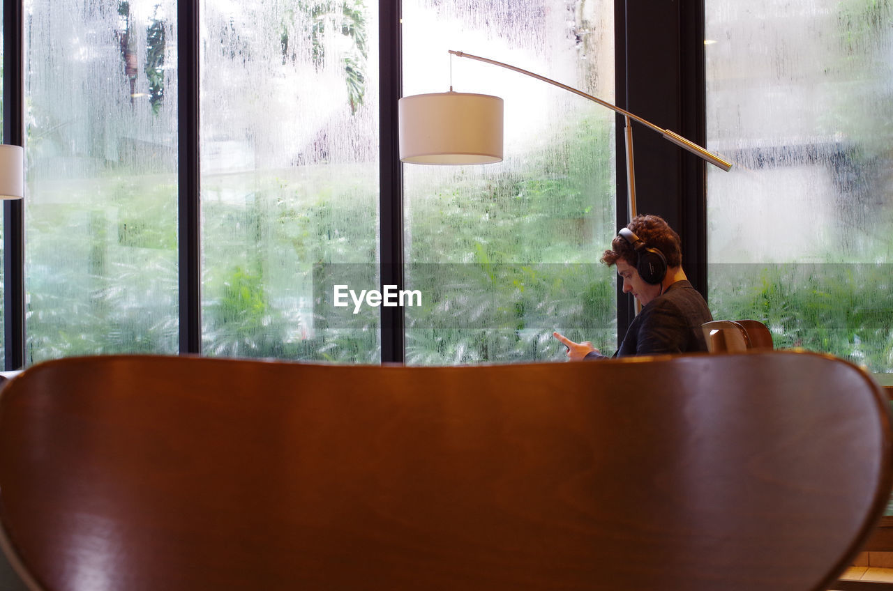 WOMAN SITTING ON CHAIR BY WINDOW