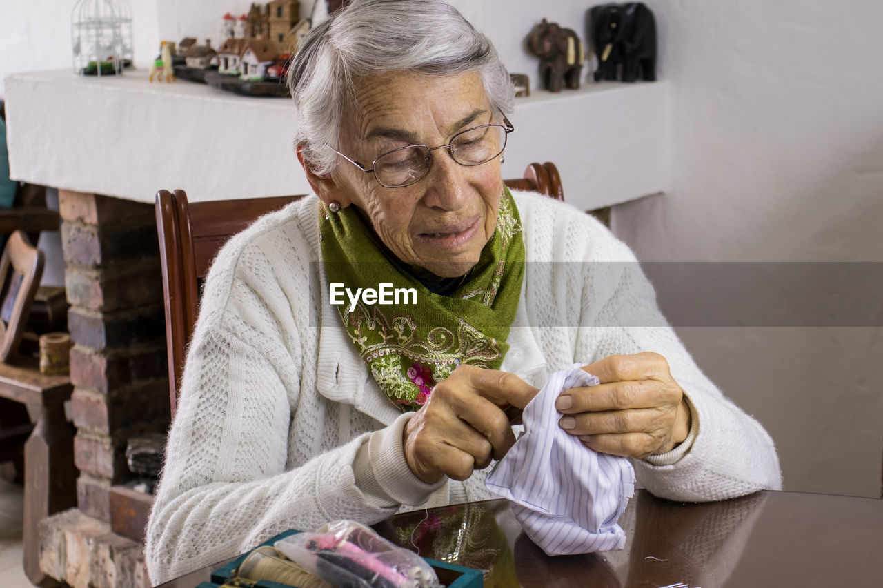 Senior woman sewing mask at home