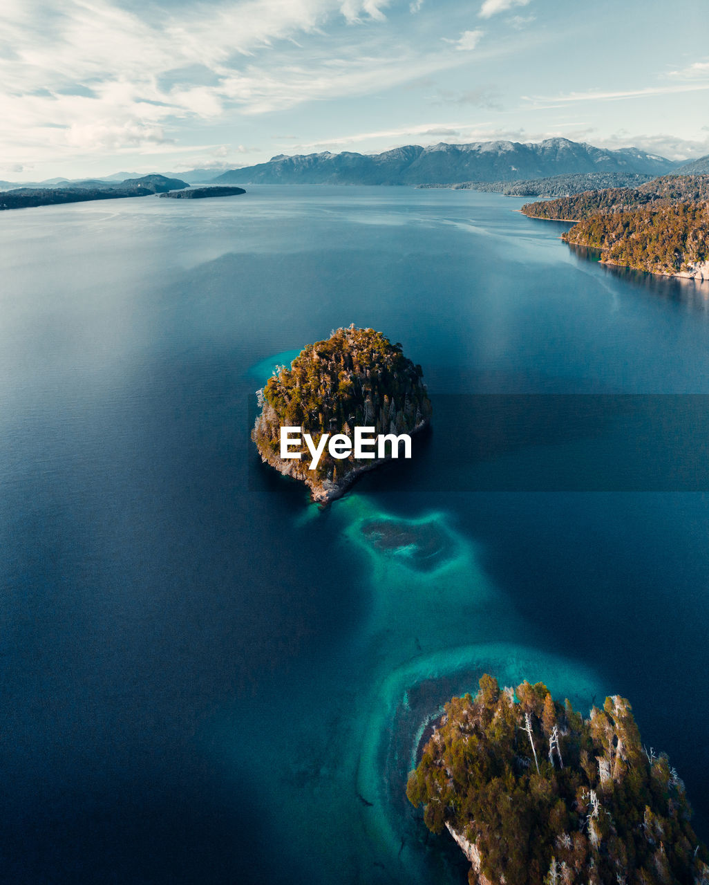 From above breathtaking aerial view of island in calm lake with turquoise water located in highlands