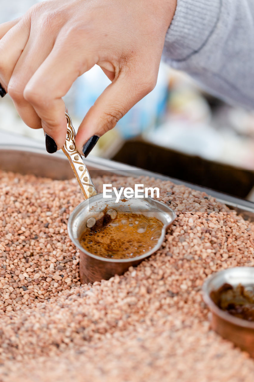 Traditional turkish, arabic coffee brewed in small copper cups in hot sand. close up shot