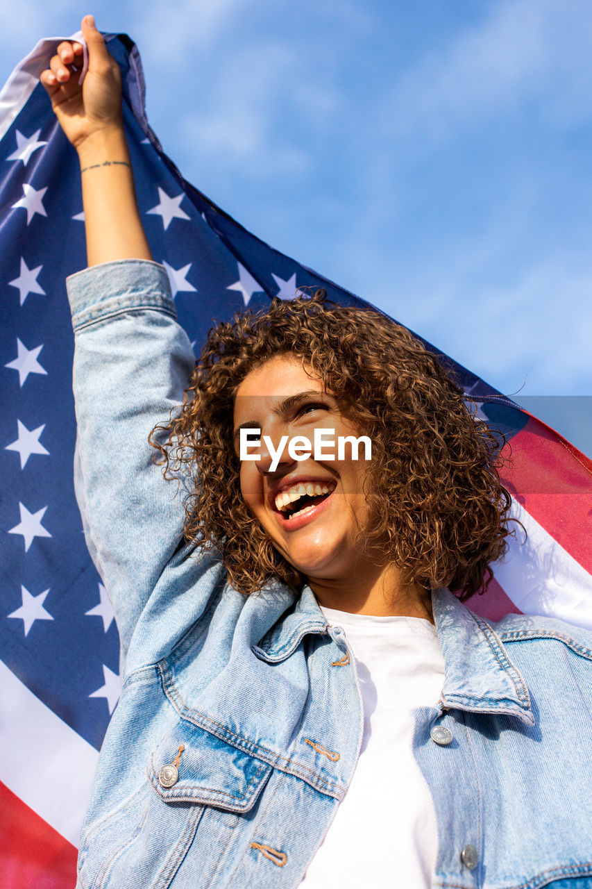 Portrait of smiling young woman holding american flag