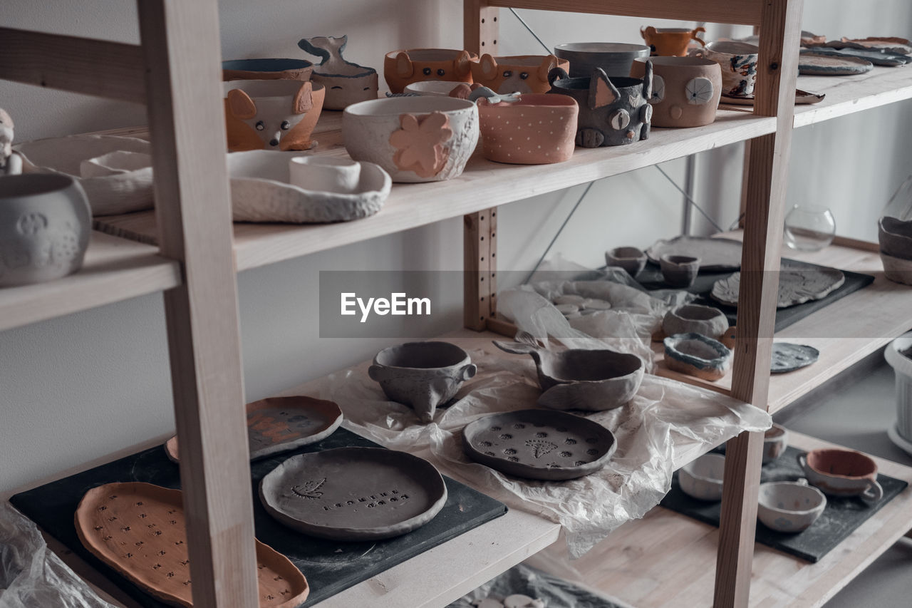 Hand made ceramics dishes on shelves, pottery workshop