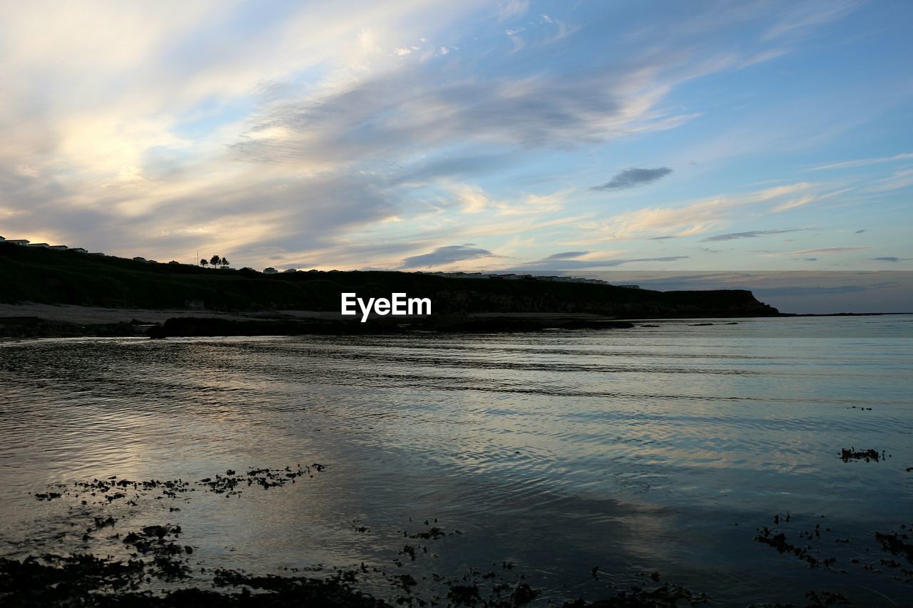 Idyllic view of beach against sky at sunset