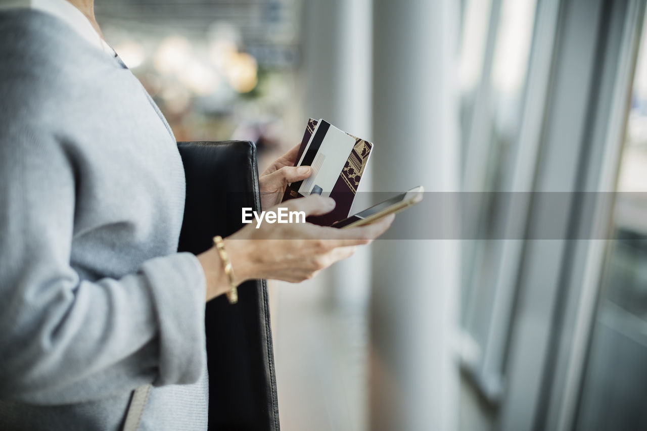 Midsection of businesswoman using smart phone at airport