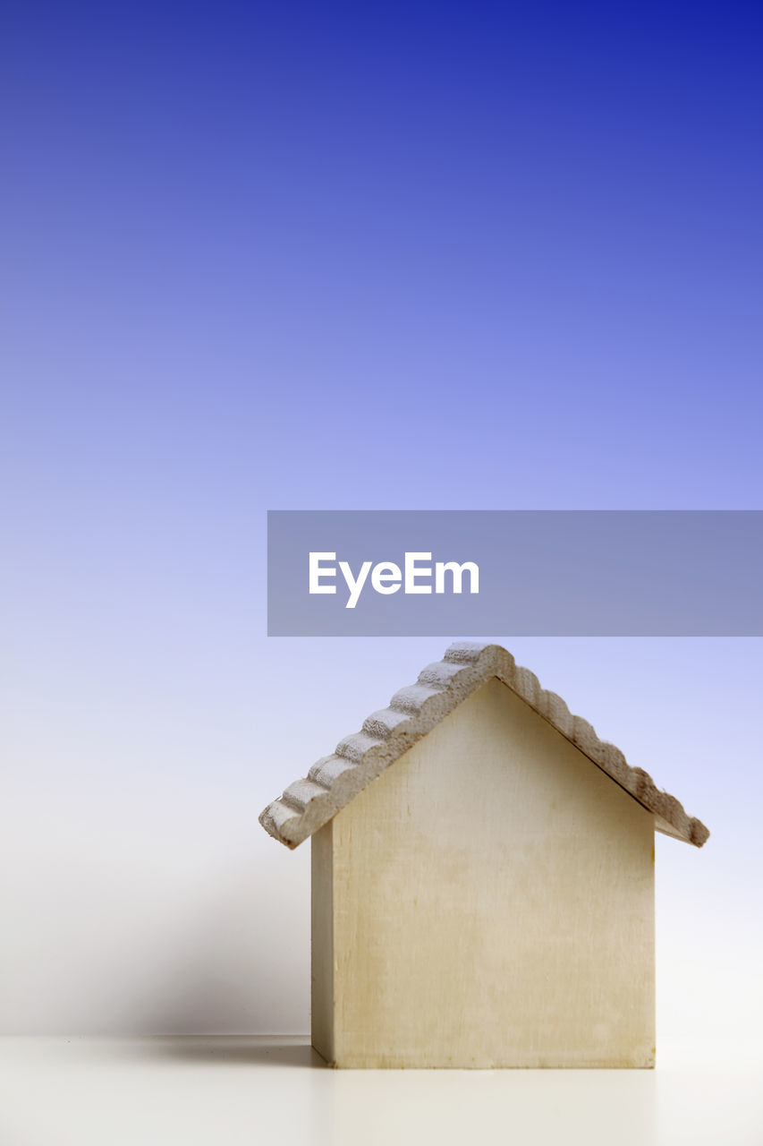 Close-up of model home on table against blue background