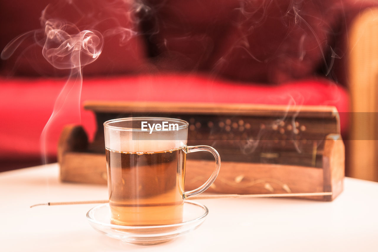 Close-up of tea glass on table with incense stick