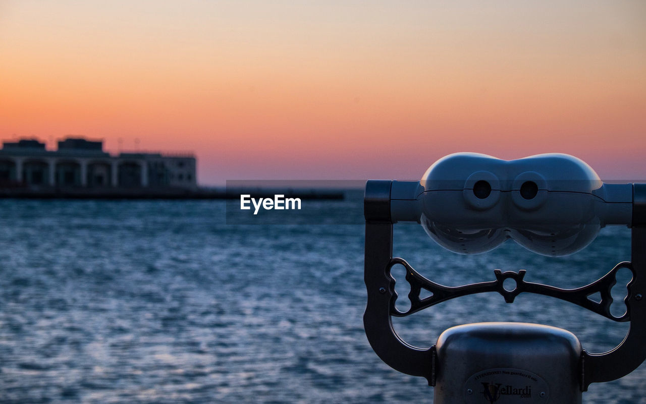 CLOSE-UP OF COIN-OPERATED BINOCULARS AGAINST CITYSCAPE