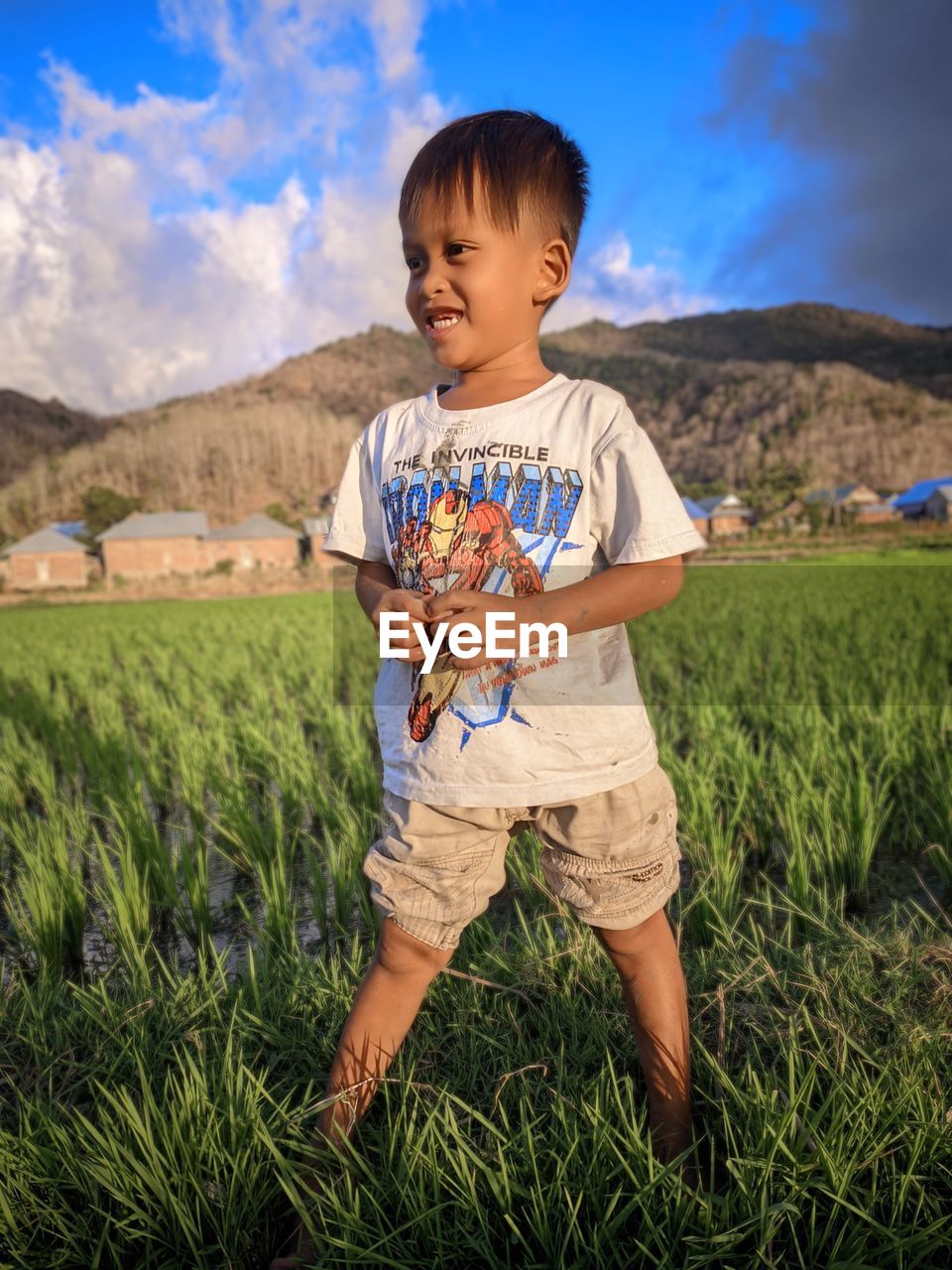 childhood, child, one person, men, land, nature, landscape, plant, field, sky, grass, full length, smiling, toddler, rural scene, cute, standing, happiness, casual clothing, agriculture, emotion, person, environment, portrait, meadow, outdoors, cloud, front view, day, food, leisure activity, innocence, growth, crop, beauty in nature, looking, food and drink, mountain, cheerful, lifestyles, blue