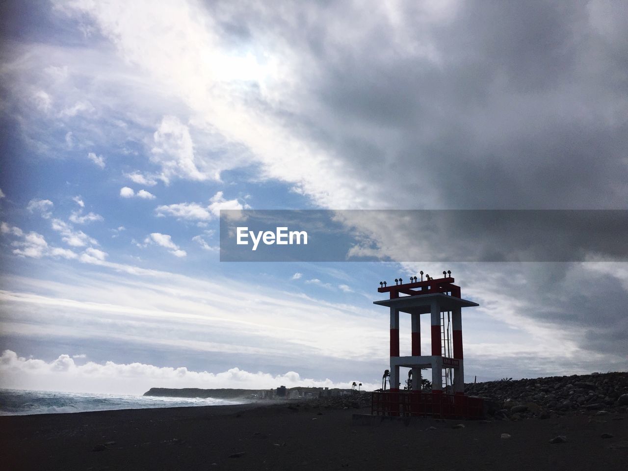 LIFEGUARD HUT ON BEACH AGAINST CLOUDY SKY