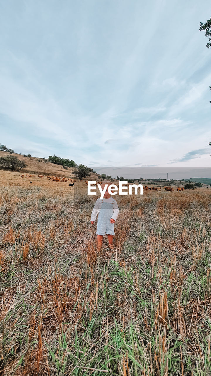 MAN STANDING ON FIELD AGAINST SKY