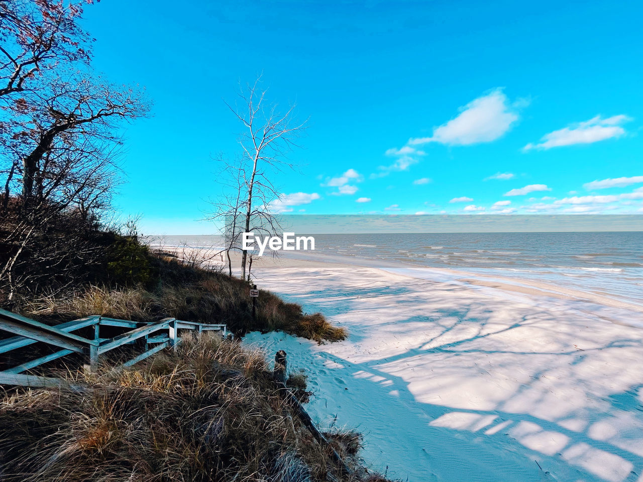 sky, water, sea, land, nature, scenics - nature, shore, ocean, blue, beauty in nature, coast, beach, plant, tree, environment, tranquility, no people, landscape, tranquil scene, winter, cloud, travel destinations, day, outdoors, travel, body of water, horizon, reflection, horizon over water, tourism, non-urban scene, sand, sunlight, snow, coastline, idyllic, wave, clear sky