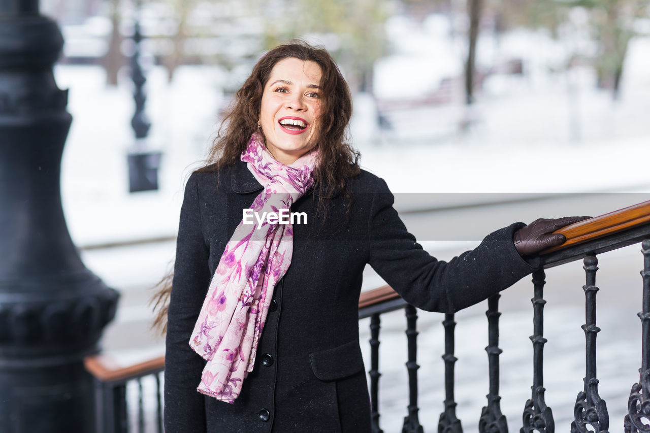 portrait of smiling young woman standing on snow