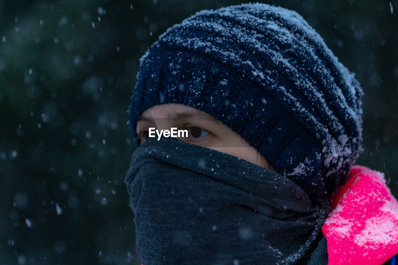 Close-up of woman covering face with textile during snowfall