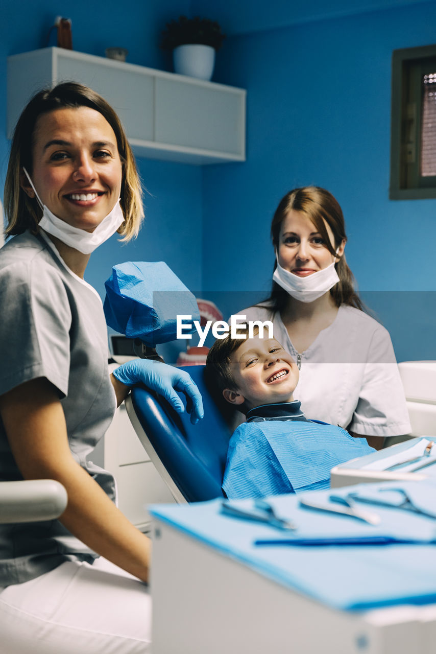 Portrait of smiling dentists and boy in medical clinic