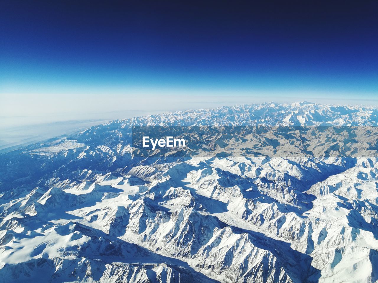 Aerial view of snowcapped mountains against blue sky
