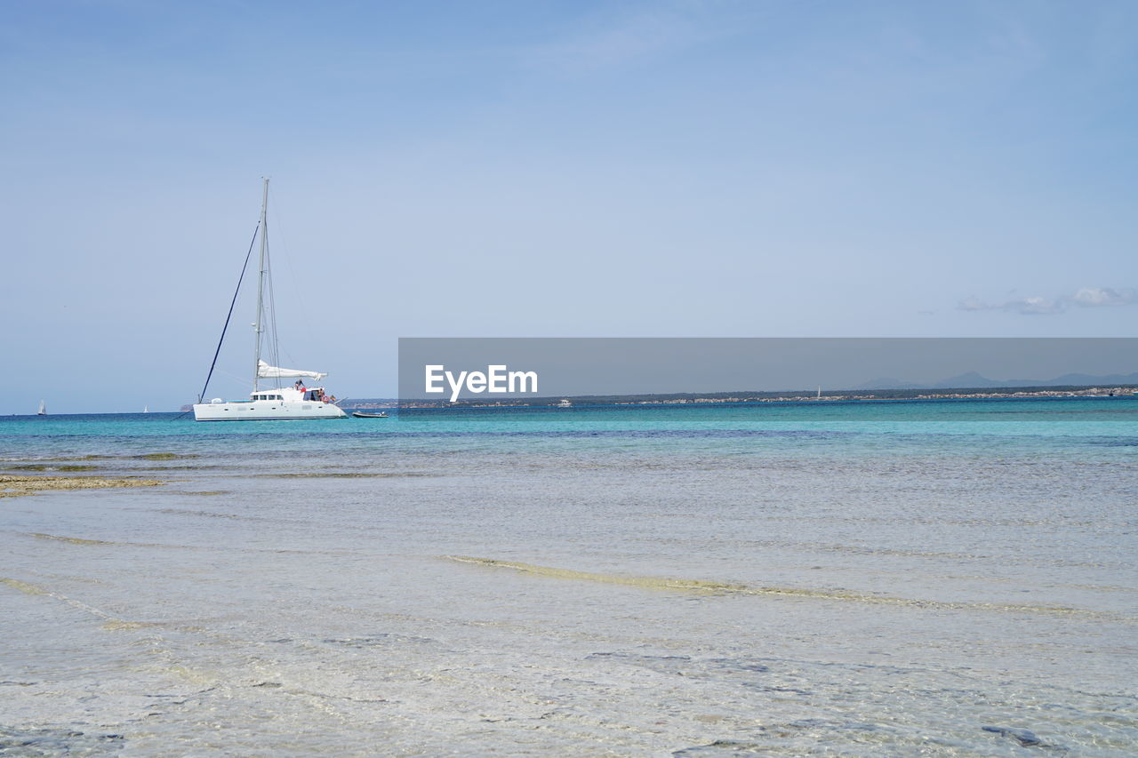 Sailboats moored on sea against clear sky